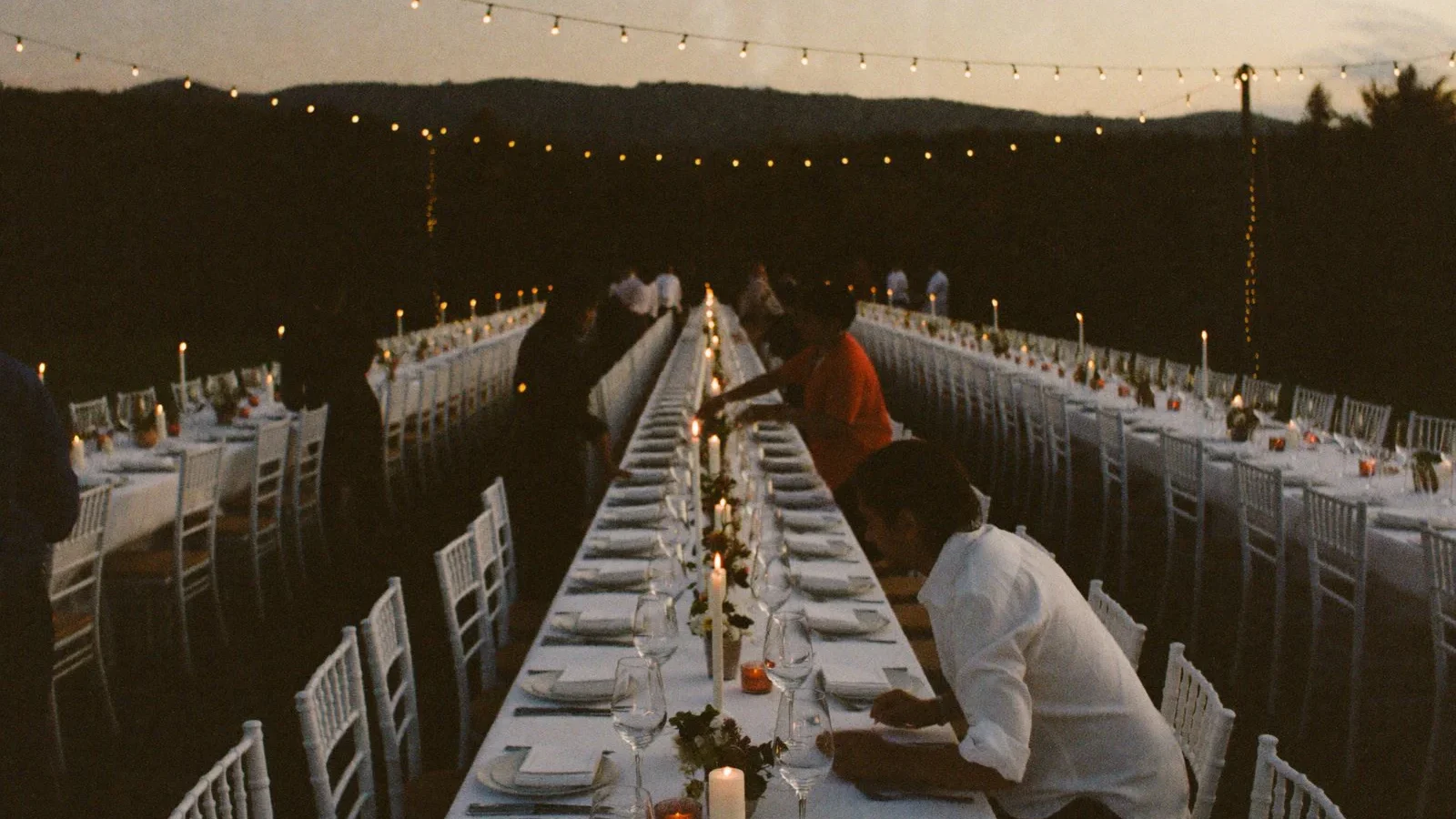 Lunga tavolata all'aperto allestita per una cena di banqueting al tramonto